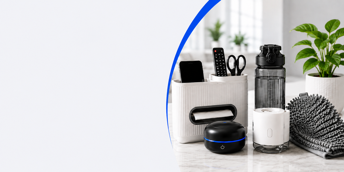 A styled tabletop scene with a white storage organizer holding a smartphone and scissors, a dark gray water bottle, a white mug, a black round device with a blue light ring, and a black-and-white patterned hairbrush, with a potted plant in the background. A large light gray rectangle obscures the center of the frame.